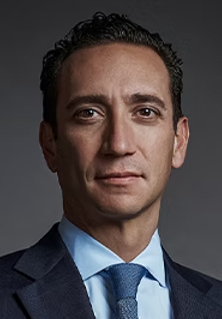 Attorney in a suit with a serious expression, posing against a dark background.