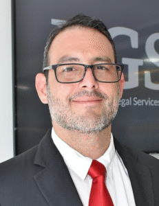 Attorney posing confidently in a suit against a background with legal services signage.