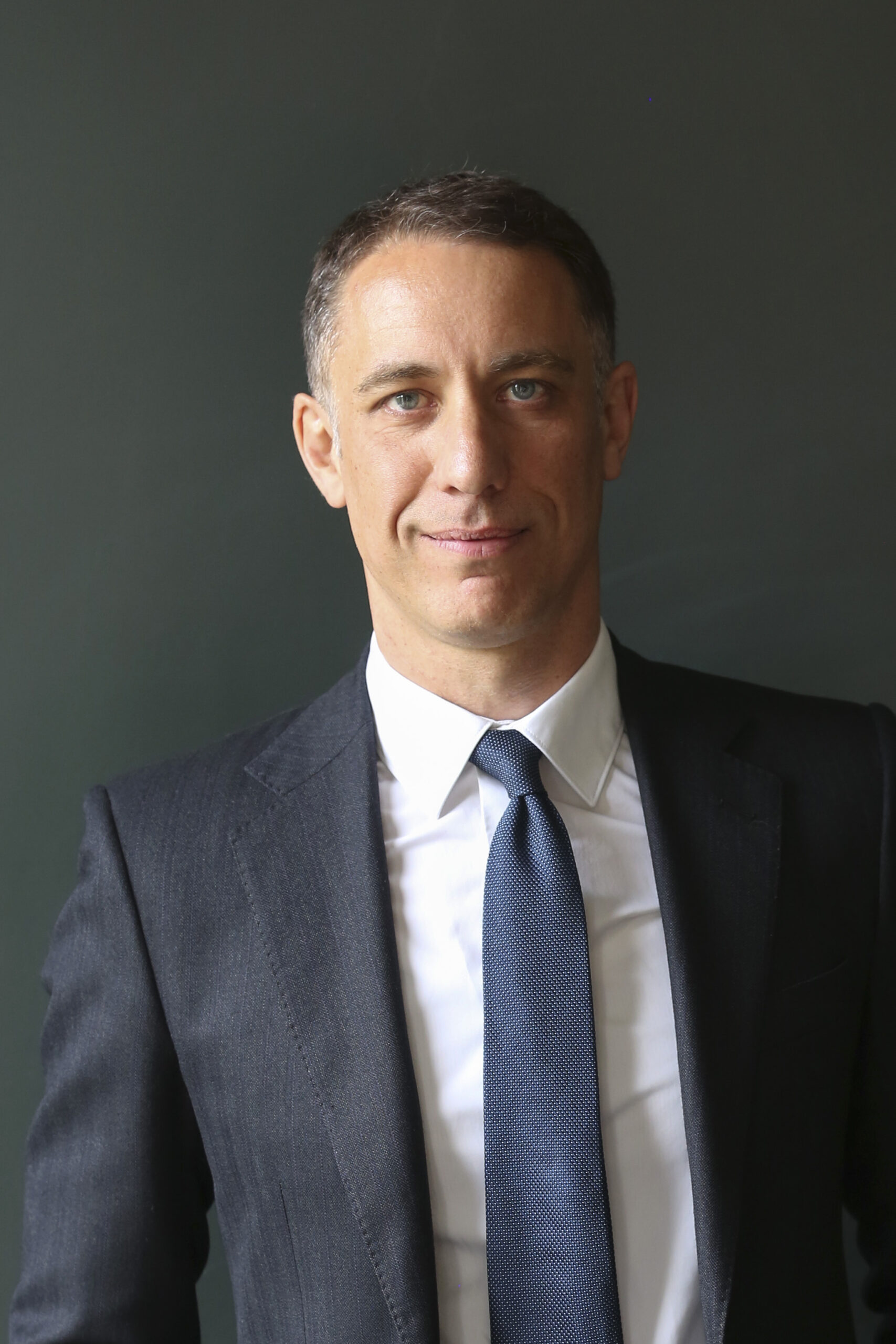 Lawyer in a tailored suit, standing against a dark background, looking confidently at the camera.