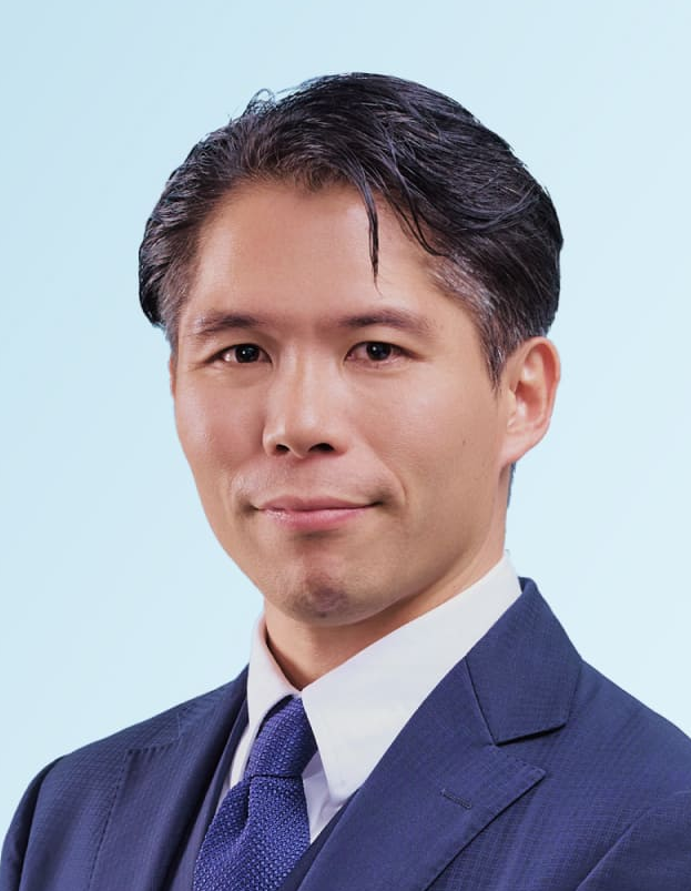 Attorney in a suit with a blue tie, smiling against a light blue background.