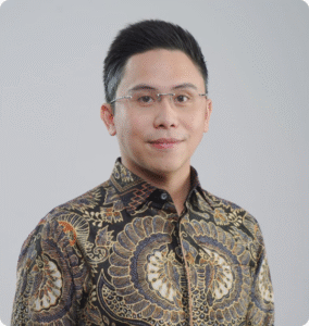 Professional wearing a patterned shirt, looking directly at the camera with a neutral background.