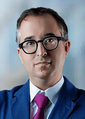 Professional appearing attorney wearing glasses and a blue suit, set against a soft blurred background.