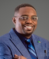 Smiling man in a blue suit and glasses, posing against a neutral background, representing a legal professional.