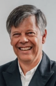 Smiling man in a suit, likely a legal professional, against a neutral background.