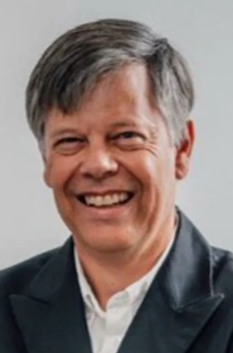 Smiling man in a suit, likely a legal professional, against a neutral background.