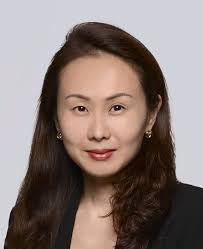 Legal professional with long hair and earrings, wearing a black blazer against a neutral background.