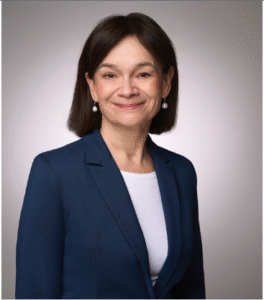 Female attorney in a professional suit, smiling against a neutral background.