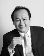 Lawyer smiling while seated, wearing a suit and tie, in a neutral setting.