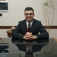 Lawyer sitting at a desk with hands clasped, in a professional office setting.