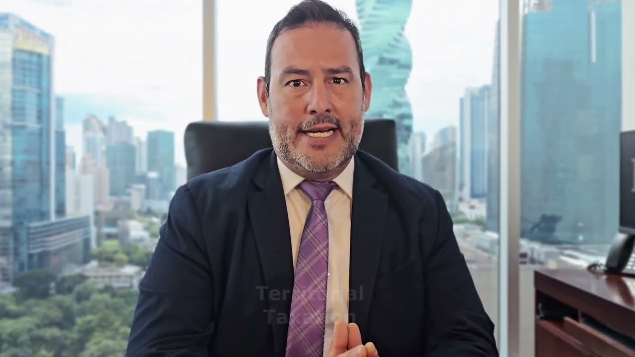 Lawyer speaking from office desk with city skyline visible through large window.