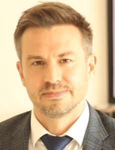 Legal professional in a suit, smiling and facing the camera in an office setting.