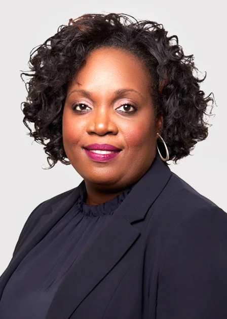 Attorney with curly hair wearing a dark blazer, posing for a professional portrait.