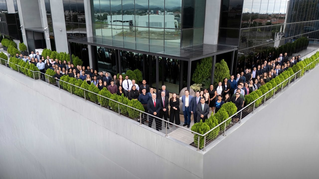 Large group of legal professionals posing outside a modern law office building.