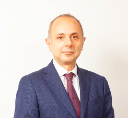 Professional in a navy suit and purple tie, posed against a neutral background, representing a legal expert.