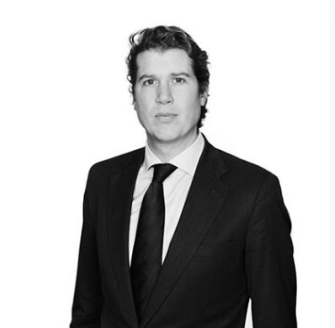 Lawyer in professional suit, posing against a plain background.