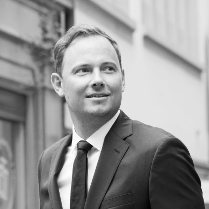 Lawyer in a suit standing outdoors, looking thoughtfully while walking near a legal office building.