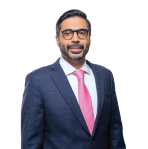 Attorney in business suit and pink tie posing confidently against a plain background.
