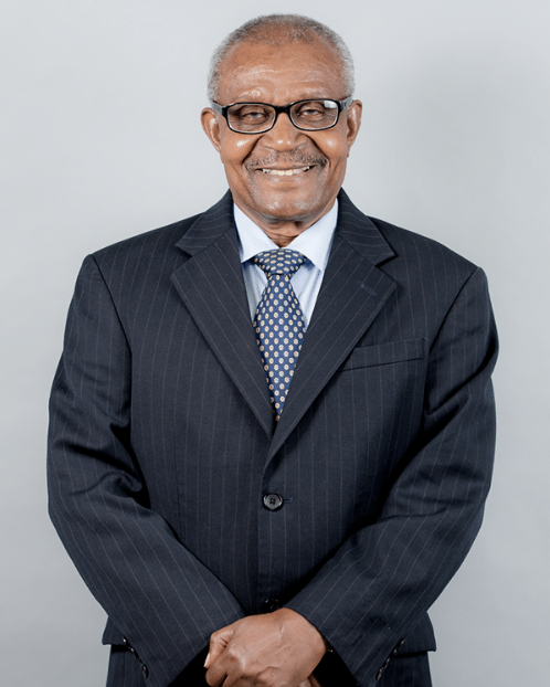 Lawyer smiling confidently in a suit, standing with arms crossed against a neutral background.