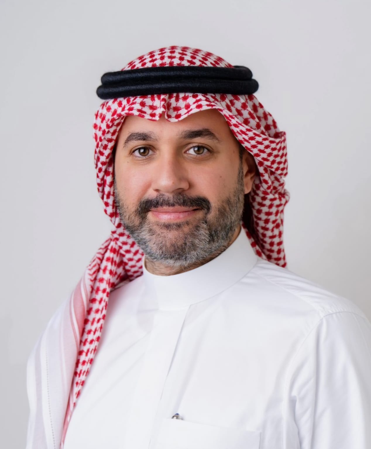Legal professional wearing traditional attire, smiling against a neutral background.