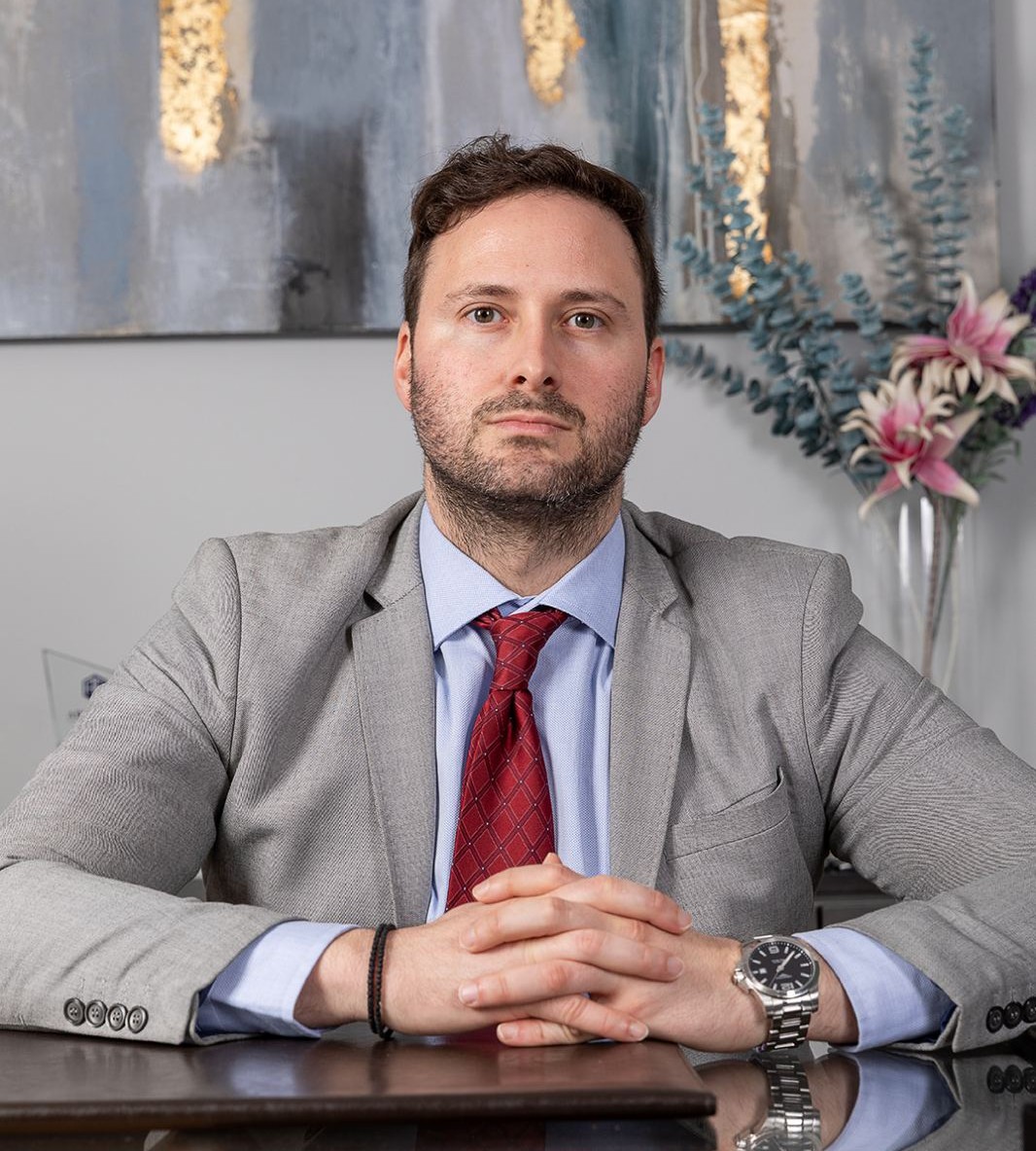 Lawyer seated at desk with hands clasped, in an office setting with modern decor.