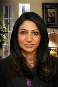 Legal professional with dark hair wearing a blazer, posed in an office setting.