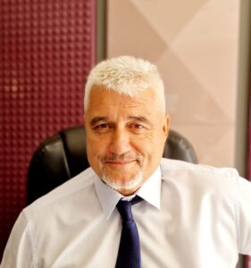 Lawyer smiling while seated in an office chair, with a professional setting and purple background visible.