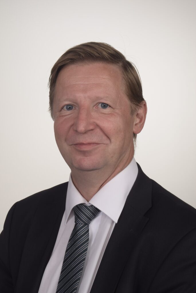 Lawyer in a suit with a tie, posing for a professional headshot against a neutral background.