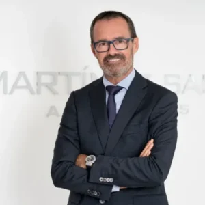 Attorney with glasses standing confidently with arms crossed in a law firm office setting.