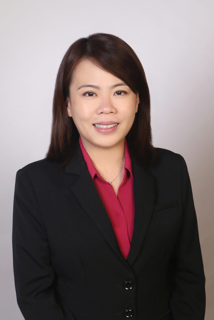 Lawyer in a black suit smiling, posing in front of a neutral background for professional profile.