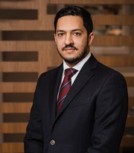 Lawyer posing for a professional portrait in an office setting with wooden panel backdrop.
