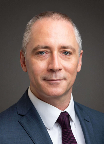 Male lawyer in a suit, professionally posed against a neutral background.