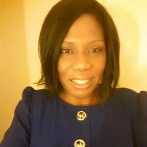 Legal professional posing for a portrait, wearing a blue top with decorative buttons.