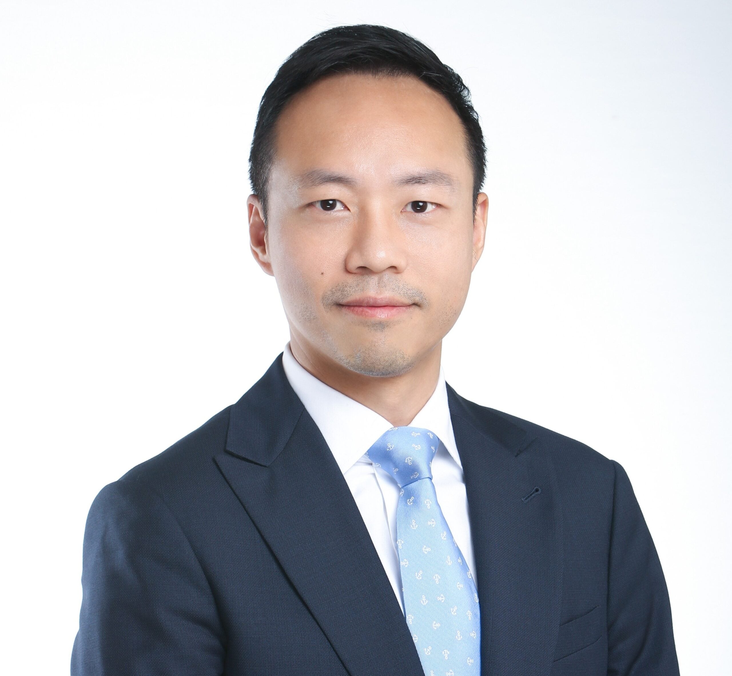 Attorney in a suit and tie against a plain background, professionally posed for a legal profile.