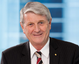 Lawyer in a striped suit smiling, with a blurred modern office background.