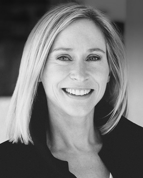Professional woman smiling, wearing a dark jacket, in a neutral background, suggesting a business or legal setting.