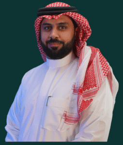 Professional man in traditional attire, standing against a solid background, conveying a formal and approachable presence.