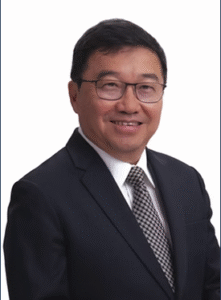 Attorney in a suit smiling against a neutral background, representing professionalism in a legal context.