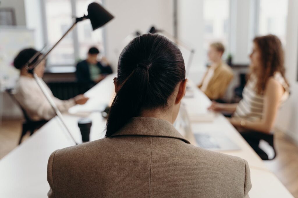 Attorney in professional attire, seated at conference table during a team meeting in a modern office.