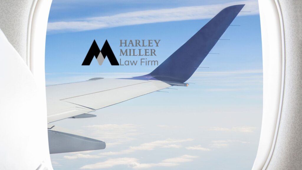 View of airplane wing against a clear sky, featuring Harley Miller Law Firm logo.