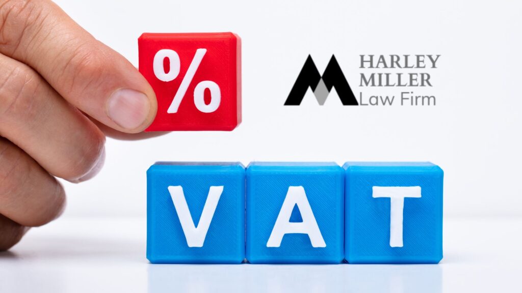Hand placing percentage symbol above colored blocks spelling "VAT" with Harley Miller Law Firm logo in background.