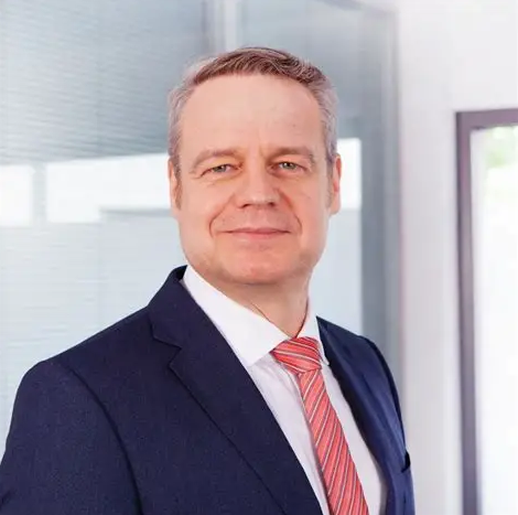 Lawyer in business suit posing confidently in a professional office setting.