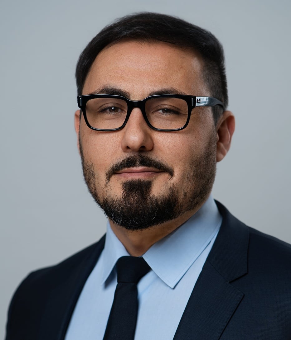 Attorney with glasses, dressed in a suit, poses for a portrait against a neutral background.