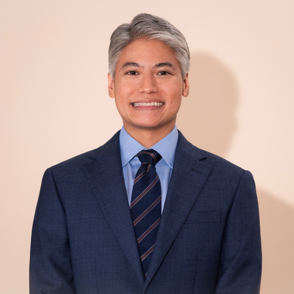 Legal professional smiling in a suit against a neutral background.