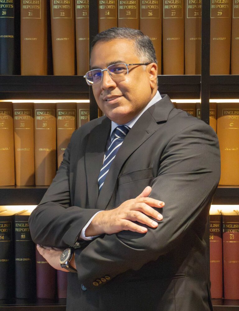 Lawyer posing confidently with arms crossed in front of bookshelves filled with legal texts.