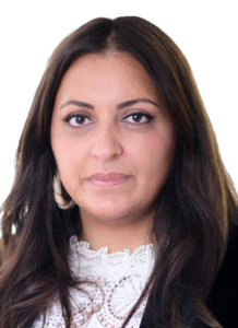 Attorney with long dark hair, wearing a white blouse, looking directly at the camera against a plain background.