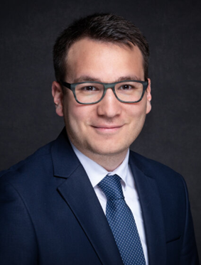 Lawyer in formal attire smiling against a dark background, conveying professionalism and approachability.