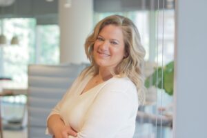 Attorney with a friendly demeanor standing with arms crossed in a modern office environment.