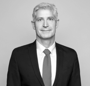 Lawyer in a suit posing against a plain background, smiling and looking directly at the camera.