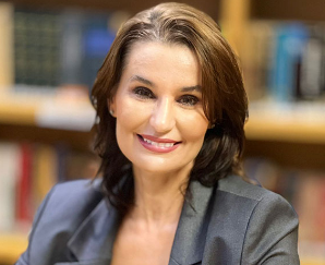 Attorney smiling confidently in a library setting filled with legal books.
