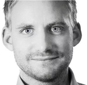 Professional headshot of a man with light hair and blue eyes, wearing a collared shirt, against a plain background.